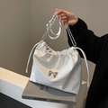 Weiße Beuteltasche mit Kroko-Prägung, silberner Kette und eleganter Schleife - Gebrochenes Weiß