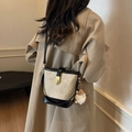 Schicke Beige-Schwarze Eimertasche mit niedlichem Plüschmonster-Anhänger am Modell - Mit Anhänger / Weiß und Schwarz