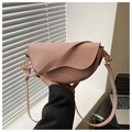 Detail of pink saddle bag with grain leather texture and gold hardware on a windowsill - Pink