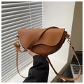 Close-up of brown saddle bag with litchi texture and metallic hardware details - Brown