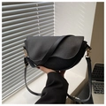 Close-up of black litchi pattern leather saddle bag with gold hardware and wavy lid - Black