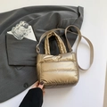 Metallic gold quilted puffer bucket bag with adjustable strap in a stylish minimalist setting - Gold