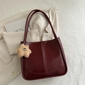 Deep red pebbled leather tote bag with a cute bear pendant on a neutral jacket - With Plush Charm / Red