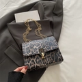 Leopard print crossbody bag with gold chain strap and oval metal clasp on grey fabric - Brown