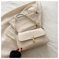 Detail shot of a cream leather crossbody bag with a rectangular gold buckle on a blazer - White