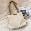 Bolso tote beige minimalista con correas marrones sobre fondo de ropa de cama blanca - Blanco Roto