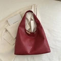 Deep red woven leather hobo shoulder bag with a wide strap on a beige blazer - Red