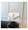 Detail of white snakeskin embossed leather handbag with gold metal clasp on stone background - White