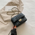 Black quilted crossbody bag with gold chain strap and turn-lock closure in chic setting - Black