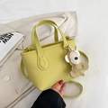 Yellow litchi pattern leather bucket bag with top handle and monkey charm accessory - Yellow