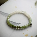 Macro shot of gradient Nephrite beads with silver lotus pendants on a paper background - Gradient Nephrite Jade Bracelet with Changle Weiyang Charm
