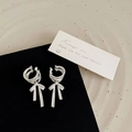Dettaglio di ear cuff a fiocco in argento opaco su un espositore nero minimalista - Argento