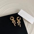 Dettaglio di orecchini ear cuff a fiocco in oro opaco con tripli anelli e nappe - Oro