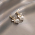 Eleganti orecchini a fiocco con perle e cristalli scintillanti su sfondo di seta grigia - Orecchini a Bottone con Perla e Fiocco
