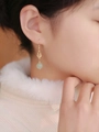 Close-up of gold Fu character earrings with translucent pale green jade-like beads - Gold Gourd Fu Character Nephrite Jade Dangle Earrings