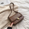 Dark brown leather square crossbody bag with gold twist lock on soft white bedding - Brown