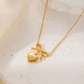 Elegant gold-plated necklace with bow and heart pendants on a textured stone surface - Gold Bow Heart