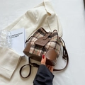 Sac seau en tweed marron et cuir avec motif à carreaux sur fond de blazer blanc - Style de base / Marron