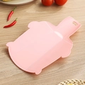 Pink pig-shaped foldable cutting board with handle on a wooden kitchen table - Pink