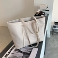 Detailansicht einer großen cremefarbenen Shopper-Tasche mit Krokodilprägung auf einem Tisch - Gebrochenes Weiß
