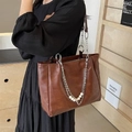 Brown leather tote bag with silver chain strap and pearl accents worn by a model - One Size / Brown