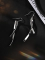 Dettaglio macro degli orecchini pendenti in argento S925 con design a nastro lucido - Oro Bianco