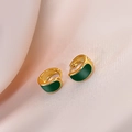 Detailopname van vintage gouden oorbellen met groen emaille op roze zijden stof - Groen