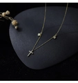 Détail d'un collier doré avec breloques cœur, étoile et croix en zircon sur fond sombre - Doré