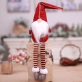 Handmade Christmas gnome plush in red hat with striped legs on a rustic wood base - Red