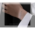 Macro shot of silver zircon pavé circle bracelet worn on wrist against black background - White Gold