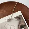 Detail van een zilveren bloemenhanger met roze zirkoon aan een fijne slangenketting - Roze Zirkonia bloem ketting