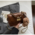 Close-up of brown quilted bag with gold chain strap and teddy bear charm accessory - With Pendant / Coffee