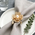 Luxury gold four-leaf flower napkin ring with central pearl on a ceramic plate - Golden Pearl Plum Blossom Style (ZWZ-CNR-003)