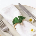 Elegant gold gingko leaf napkin ring with green enamel finish on white linen napkin - Default