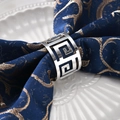 Silver Greek Key metal napkin ring on navy blue linen over a white ceramic plate - Silver Greek Key