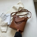 Retro brown faux leather bucket bag with woven handle and gold hardware on white blazer - Brown