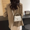Mini borsa a mano trapezoidale argento metallizzato su un blazer beige chic - Argento