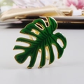 Detailed close-up of green monstera leaf napkin ring with golden metal base and enamel finish - Alloy Green
