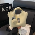Beige Beuteltasche mit silbernem Verschluss und Herzanhänger auf schwarzer Box - Basisstil / Hellgelb