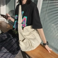 Sac bandoulière en toile blanche avec poches multiples présenté sur un banc extérieur - Blanc Cassé
