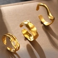 Dettaglio di tre anelli dorati irregolari a onde su un piedistallo marrone - Set di 3 Pezzi di Anelli Aperti Irregolari Oro (C6479) / Oro
