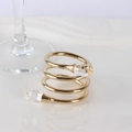 Golden spiral napkin ring with double crystal drops on a glossy white surface - Gold