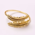 Macro shot of double golden feather open ring with detailed engraving on pale background - Gold