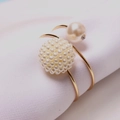 Elegant gold napkin ring with white pearl cluster and rhinestone accent on white fabric - Bayberry Ball Style