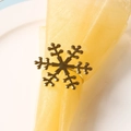 Detail of a golden snowflake napkin ring with a polished metallic finish on a table - Gold Snowflake