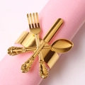 Golden napkin ring featuring a cutlery design with fork and spoon on pink napkin - Gold