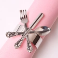 Detail of silver napkin ring featuring miniature cutlery design on pink fabric - Silver