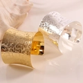 Macro detail of wide metal napkin rings with embossed rose patterns in gold and silver - Gold