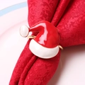 Kerstmuts servetring met rood emaille en gouden afwerking op een feestelijk rood servet - Kerstmuts Stijl