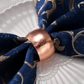 Rose gold drum napkin ring with hammered texture on a dark blue embroidered cloth - Hammered Texture (Rose Gold) / Rose Gold
